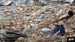Seorang anak laki-laki Kamboja menarik ban sepeda di tempat pembuangan sampah Stung Meanchey di Phnom Penh.