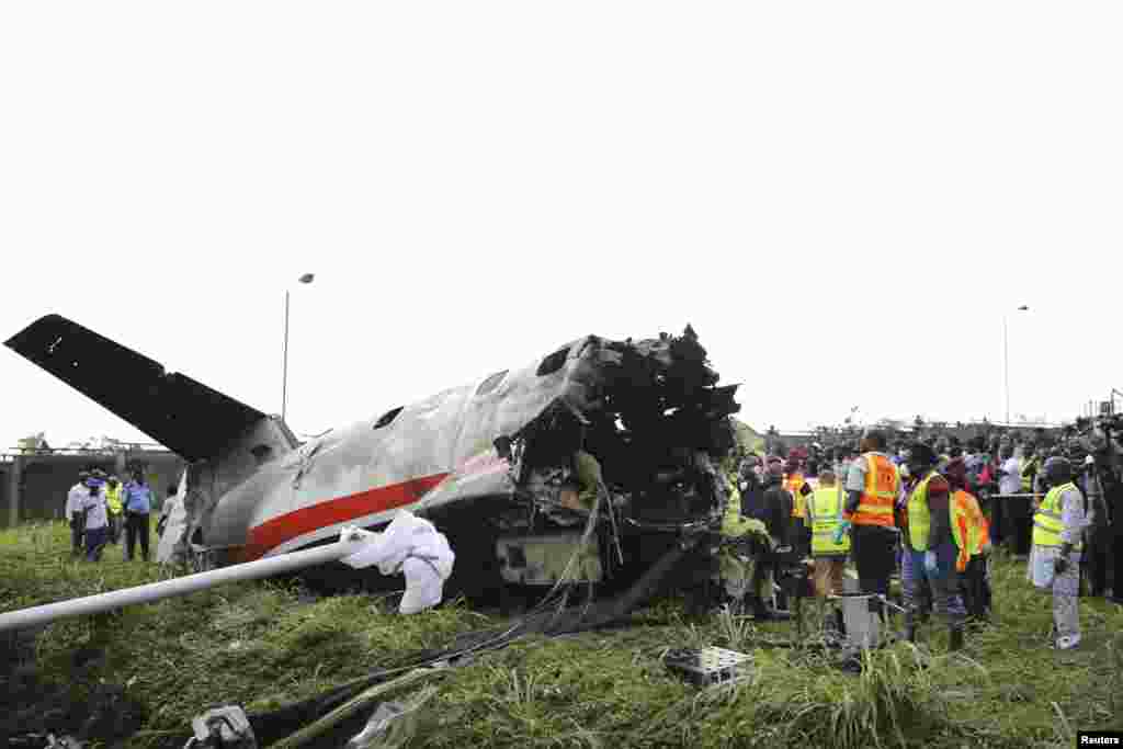 Petugas penyelamat berdiri di dekat ekor pesawat di lokasi kecelakaan dekat bandara internasional Lagos, Nigeria. 15 penumpang tewas dalam kecelakaan ini.
