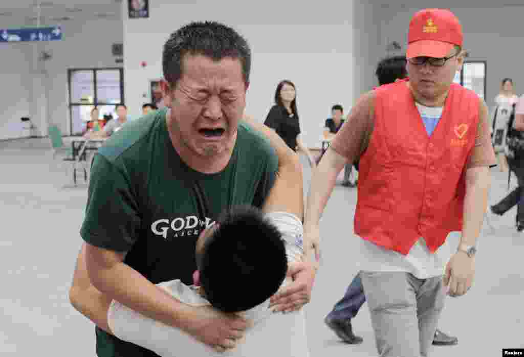 Một người đàn ông ôm con khóc tại trung tâm chăm sóc nạn nhân động đất tại thị trấn Lỗ Ðiền, tỉnh Vân Nam, Trung Quốc, ngày 3/8/2014.
