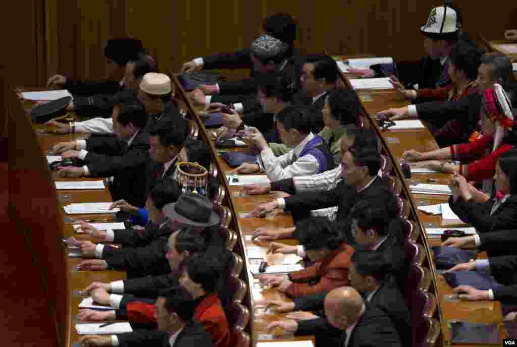 Para delegasi memencet tombol untuk menyatakan persetujuan atas proposal rancangan undang-undang dalam sidang pembukaan Kongres Nasional Rakyat China di Beijing (5/3). (AP/Ng Han Guan)