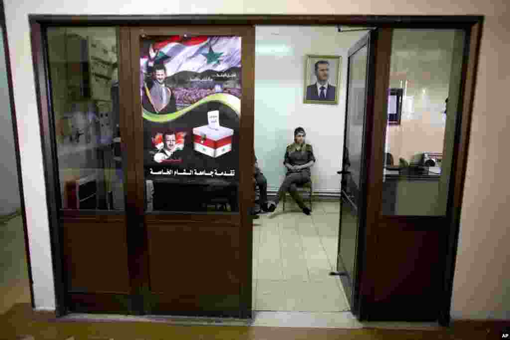 A Syrian soldier sits under the portrait of President Bashar al-Assad at a polling station in Damascus, June 3, 2014.
