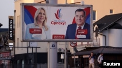 Warga berjalan melintasi papan iklan yang berisi gambar tokoh politisi Milorad Dodik dan Zeljka Cvijanovic dari Aliansi Independen Sosial Demokrat di Gradiska, Bosnia dan Herzegovina, pada 28 September 2022. (Foto: Reuters/Dado Ruvic)