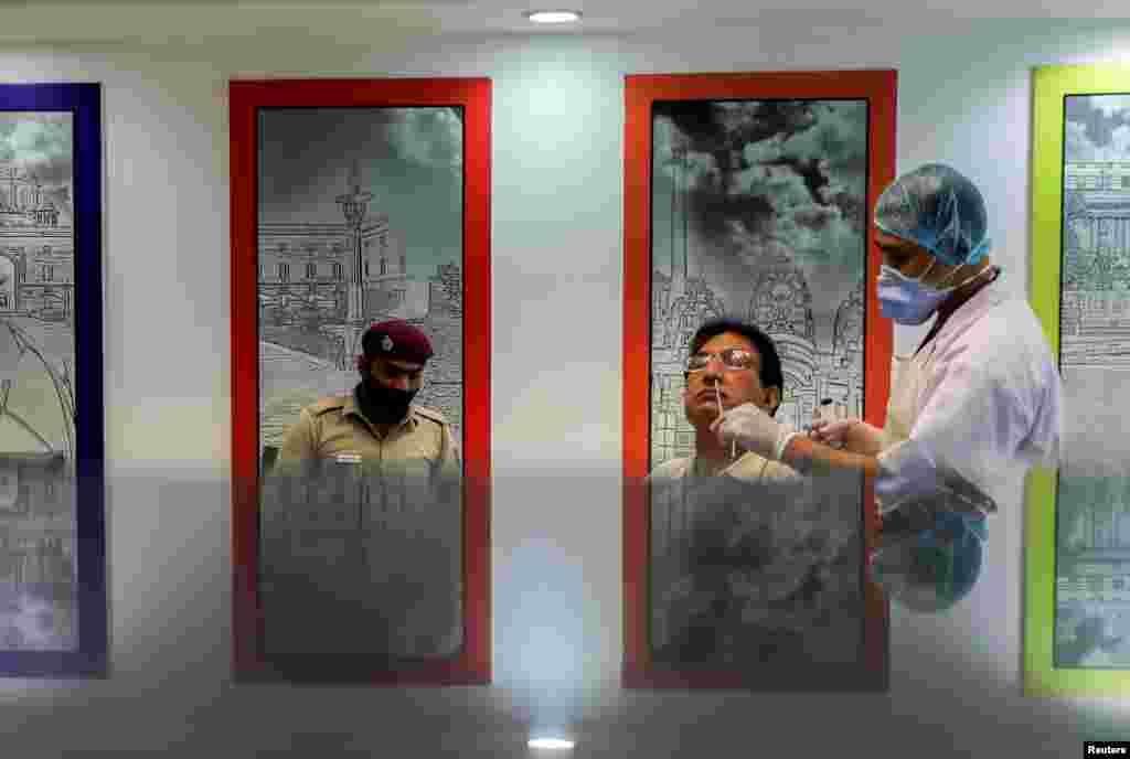 A healthcare worker wearing a protective face mask collects a swab sample from a man, amidst the spread of the coronavirus disease (COVID-19), in New Delhi, India.