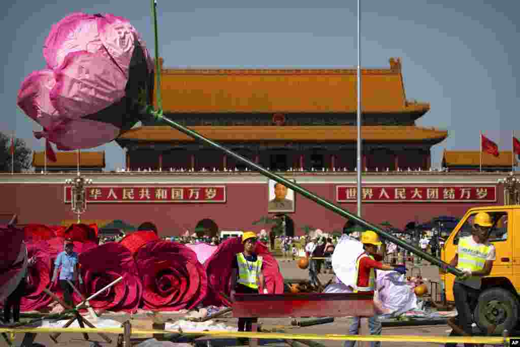 Para pekerja berusaha memasang instalasi 'bunga mawar' di Lapangan Tiananmen, Beijing.