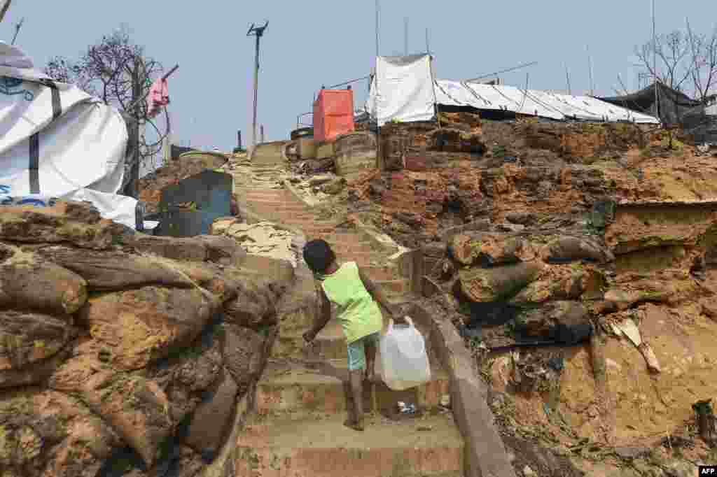 A Rohingya refugee child carries water to her temporary shelter days after a fire burnt down homes at a refugee camp in Ukhia, in the southeastern Cox's Bazar district, Bangladesh.