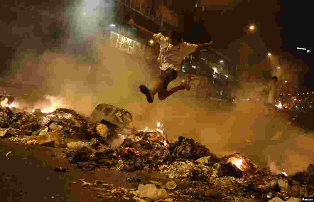 A boy jumps over a barricade of burning garbage that supporters of opposition leader Henrique Capriles used to block a street, as they demonstrated for a recount of the votes in Sunday's election, in Caracas, April 15, 2013. 
