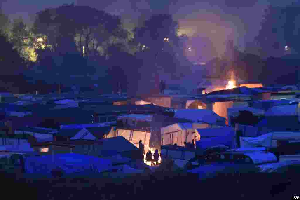 Para migran menyalakan api unggun di kamp "Jungle" menjelang evakuasi migran dari kamp di kota Calais, Perancis utara.