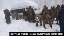 Seorang tentara membersihkan salju di bawah kendaraan yang terdampar setelah hujan salju lebat di Murree, Pakistan 8 Januari 2022. (Foto: Inter Services Public Relations/ISPR via REUTERS)