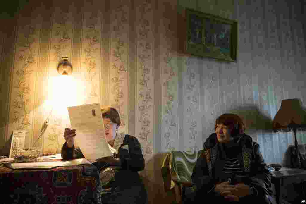 Ludmila Ezhova, perempuan lansia berusia 80 tahun (kiri) siap mencoblos kartu suara yang dibawa petugas pemilu ke rumahnya di Moskow, Rusia.