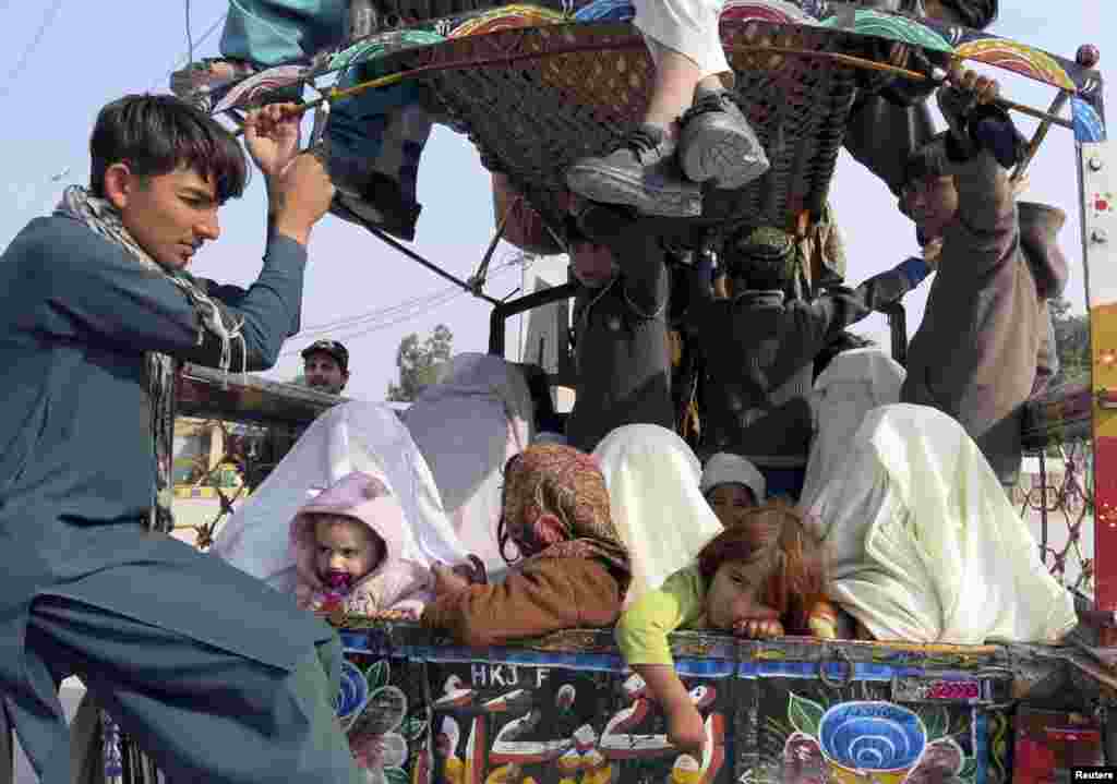 Families sit at the back of a van with their belongings while fleeing a military offensive against the Pakistani Taliban, as they enter Bannu in Khyber Pakhtunkhwa province, Jan. 22, 2014.